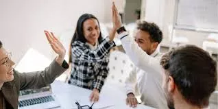 Equipo de trabajo reunido en oficina celebrando un logro laboral durante una reunión colaborativa