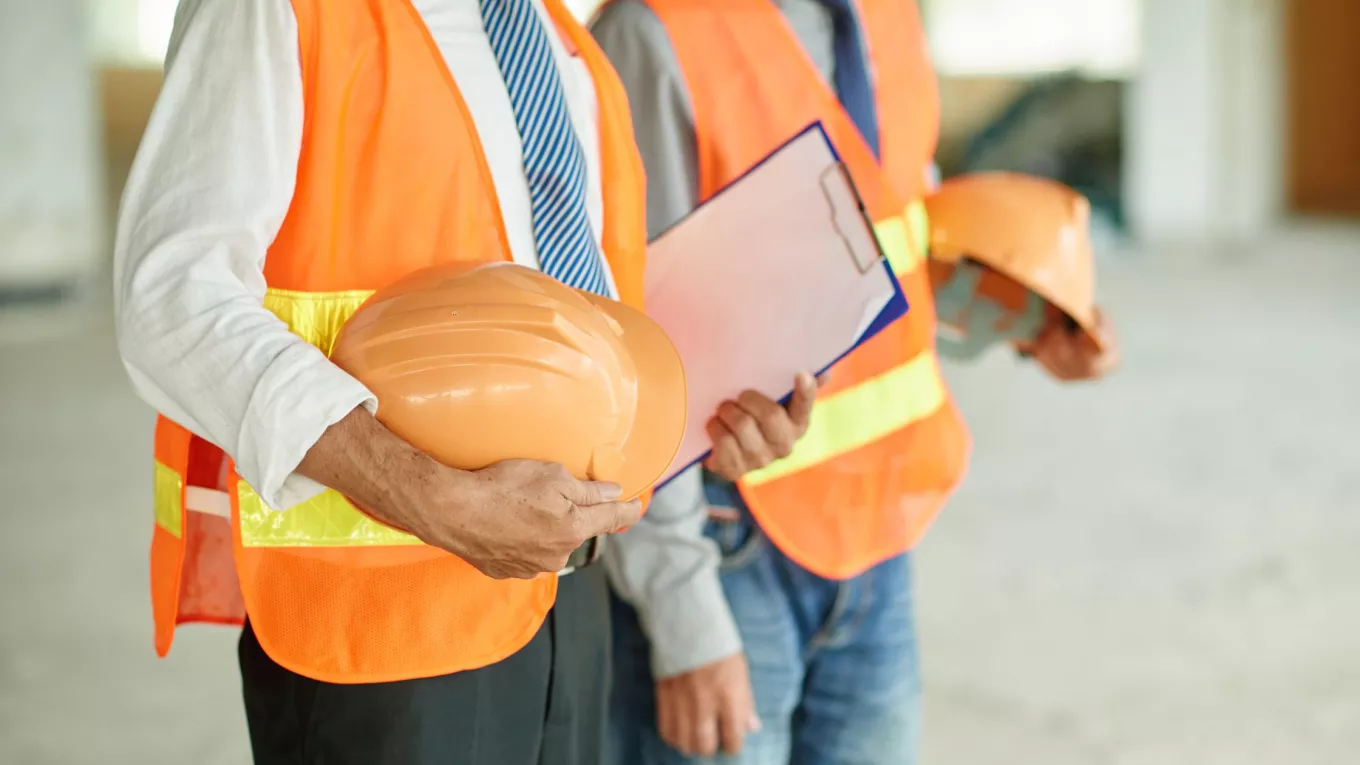 Trabajadores con chalecos de seguridad y cascos para prevenir riesgos de salud ocupacional 