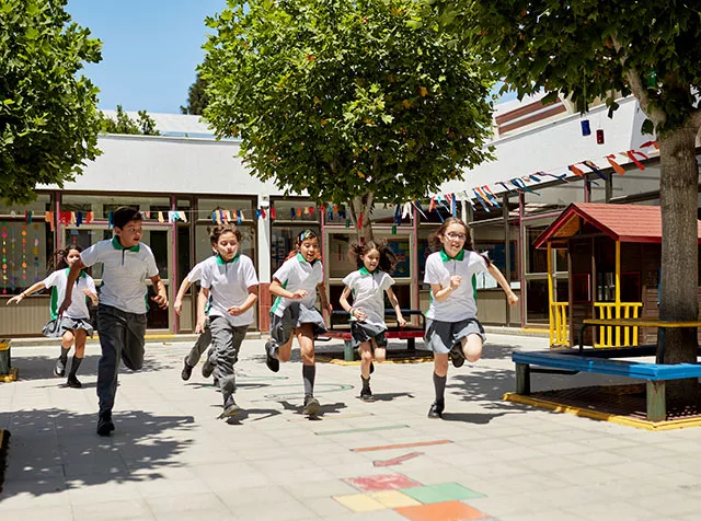 Niños corren juntos en el patio de una escuela en Chile.