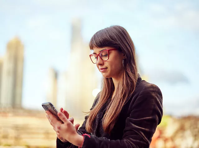 Joven profesional accede al celular al aire libre.