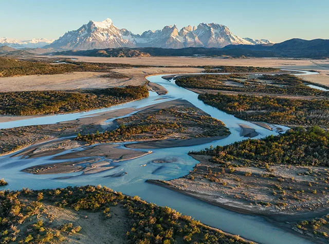 Foto muestra un paisaje del Parque Nacional de Chile. Una cordillera nevada con pequeños ríos cortando la naturaleza.