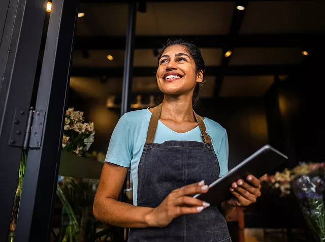 Una mujer sonriente frente a su local