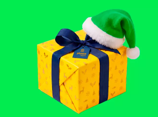 Una caja de regalo amarilla con un gorro verde de Viejito Pascuero.