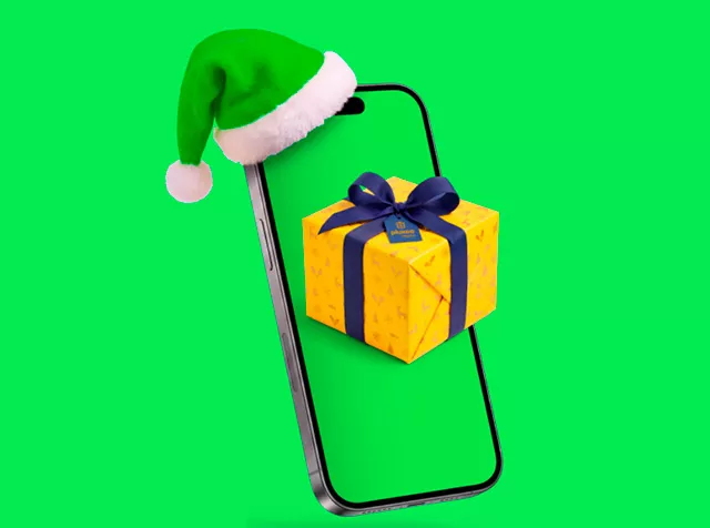 Celular con gorro de Viejito Pascuero y un regalo amarillo delante