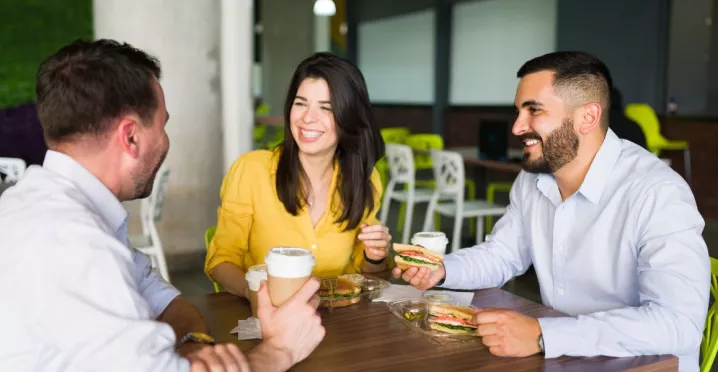 Compañeros de trabajo riendo mientras comparten el almuerzo en la oficina