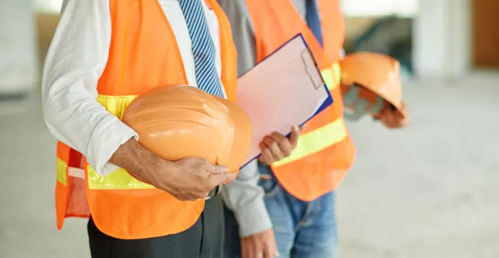 Trabajadores con chalecos de seguridad y cascos para prevenir riesgos de salud ocupacional