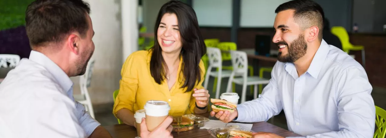 Compañeros de trabajo riendo mientras comparten el almuerzo en la oficina