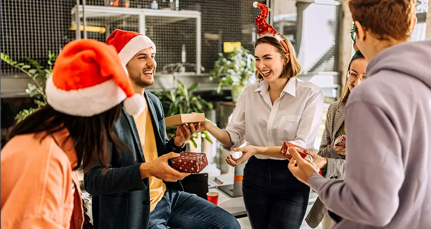 Compañeros de trabajo celebran la Navidad intercambiando regalos en un amigo secreto.