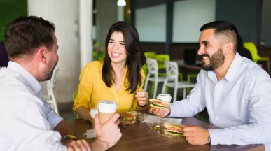 Compañeros de trabajo riendo mientras comparten el almuerzo en la oficina