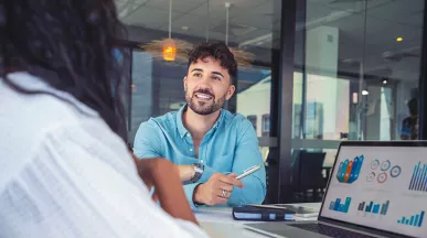 La foto muestra a dos personas conversando en la oficina.
