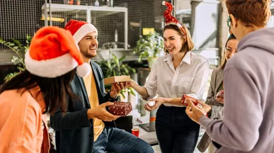 Compañeros de trabajo celebran la Navidad intercambiando regalos en un amigo secreto.