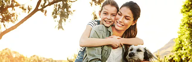 Madre e hija pasean en el parque con su perro