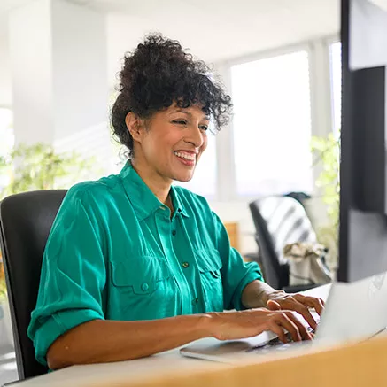 Foto muestra a una mujer trabajando feliz en el computador.