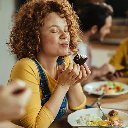 Joven come un postre durante el almuerzo de trabajo