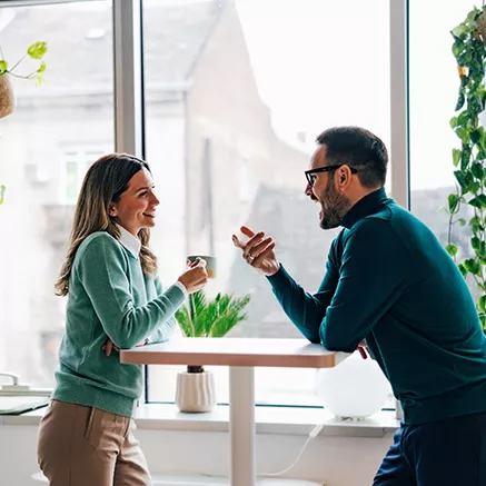 Dos colegas de trabajo conversan animadamente durante una pausa en sus actividades 
